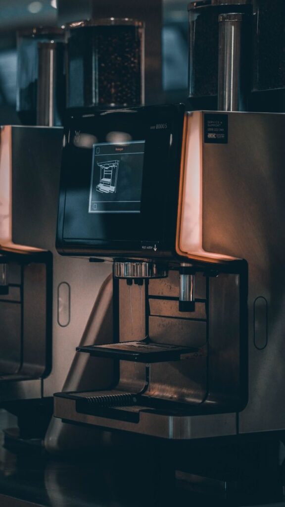 Close-up of a sleek coffee machine with touchscreen interface in a cafe setting.